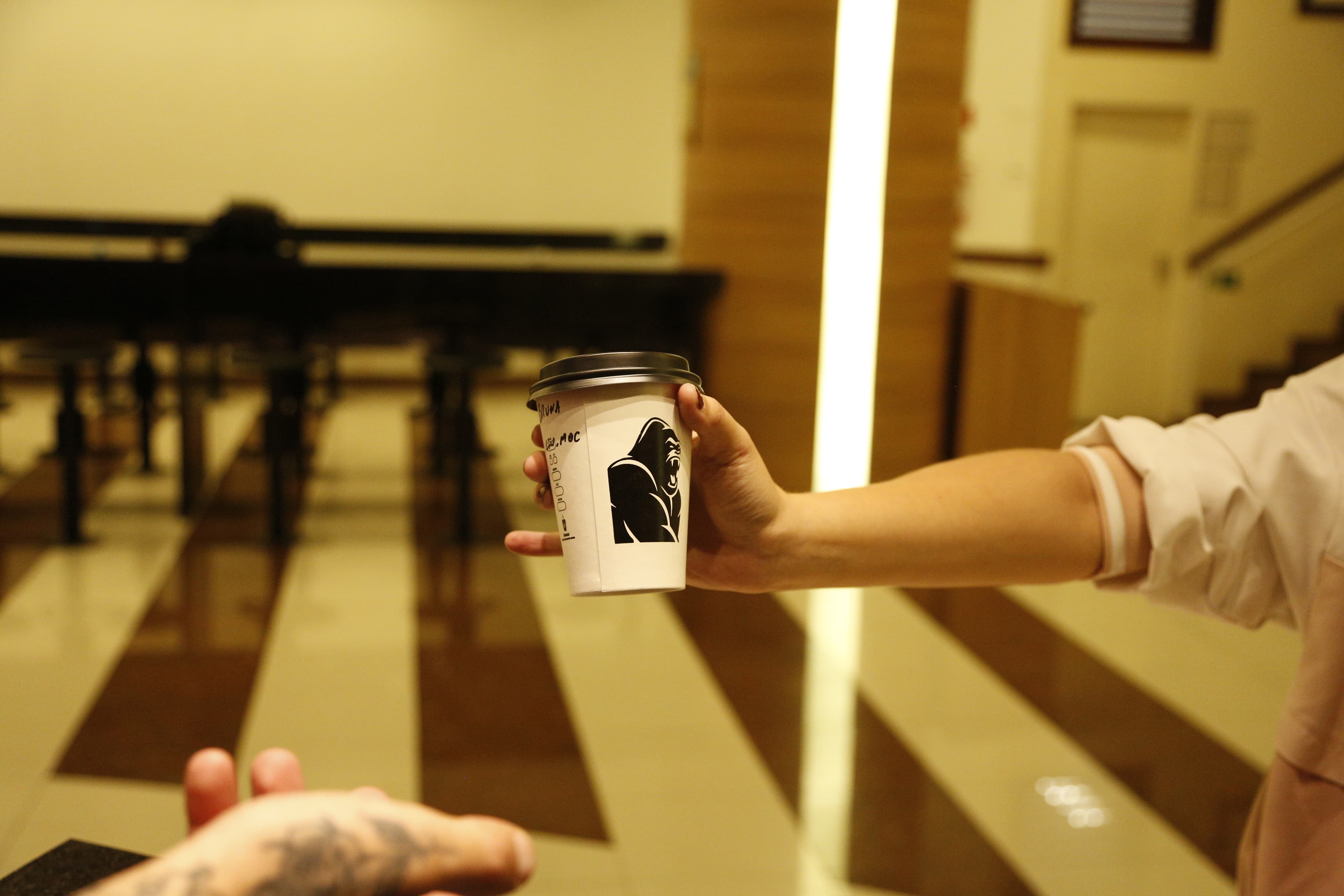 Barista da Robusta Coffee Co. entregando uma bebida no balcão